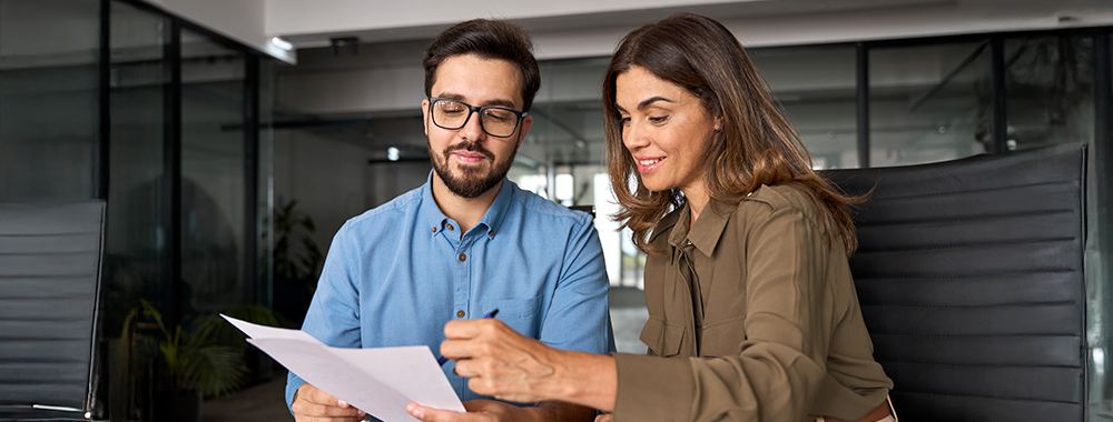 Duas pessoas analisando um documento em ambiente profissional, representando negociação contratual.