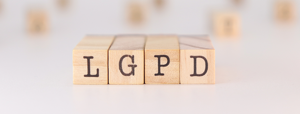 Blocos de madeira com as letras LGPD, representando a Lei Geral de Proteção de Dados e sua aplicação na gestão escolar.