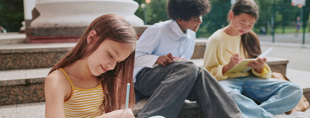 Crianças e adolescentes estudando ao ar livre, representando programas escolares de contraturno com atividades extracurriculares.